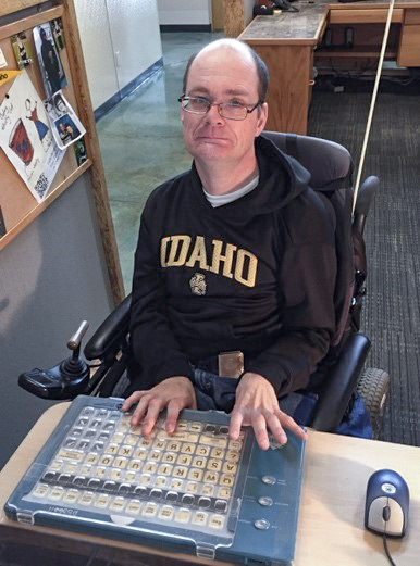 An Idaho Center on Disabilities and Human Development employee with a disability using an over-sized keyboard to type.