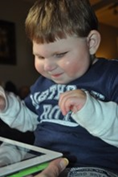 Young boy smiling at iPad.